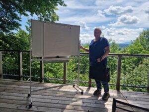 Wirtschaftsmediatorin Julia Gebert auf Plattform im Wald mit Flipchart und wunderbaren Ausblick